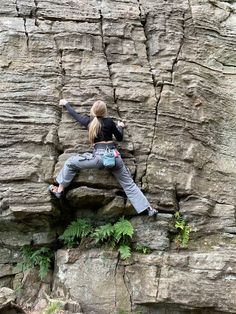 a woman climbing up the side of a cliff