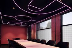 an empty conference room with red walls and black leather chairs in front of a long white table