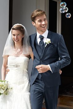 a bride and groom walking down the street in front of bubbles that are floating up in the air