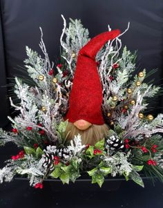 a gnome's head surrounded by greenery and pine cones