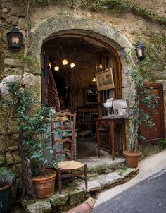 an old stone building with potted plants in the doorway and other items on display