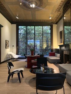 a living room filled with furniture and a fire place in front of two large windows