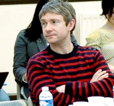 a man sitting at a table with his arms crossed and looking off to the side