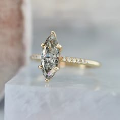 an oval cut diamond ring on top of a marble block