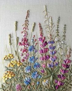 an arrangement of wildflowers on a white background with green stems and purple flowers