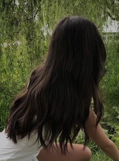 a woman sitting in the grass with her back to the camera