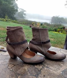 a pair of women's shoes sitting on top of a stone floor next to a field