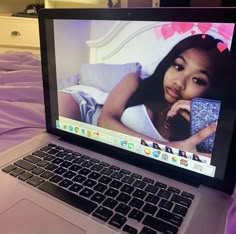 an open laptop computer sitting on top of a bed next to a purple comforter