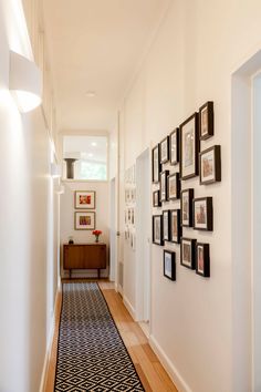 a long hallway with pictures on the wall and framed photos on the wall above it