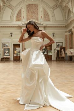 a woman in a white dress is standing on the floor with her hands behind her head