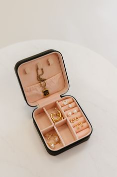 an open suitcase filled with jewelry on top of a white table