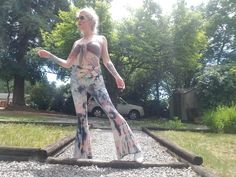 a woman standing on top of a train track in the middle of a park with trees behind her