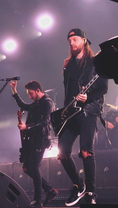 two men on stage with guitars and microphones