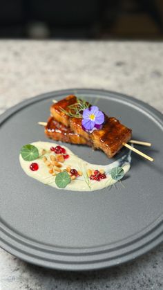 two pieces of food on a plate with toothpicks and flower garnish