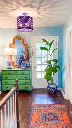 a hallway with blue walls and wooden flooring has a green plant in the corner