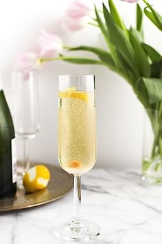 a glass filled with champagne sitting on top of a table next to bottles and flowers