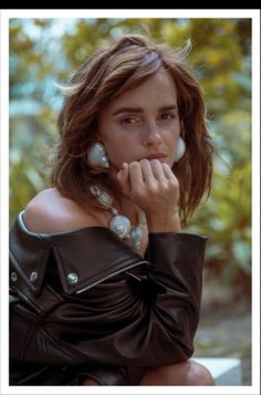 a woman in a leather jacket is talking on the phone with her hand near her face