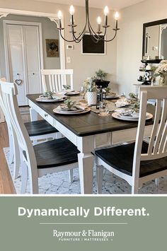 the dining room table is set with black and white plates, silverware, and flowers