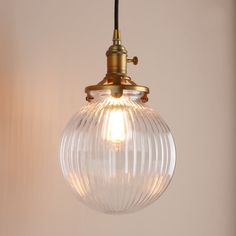 a light fixture with a glass globe hanging from it's side and a black cord attached to the end