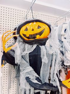 a halloween decoration hanging on a wall in a store with lots of clothes and pumpkins