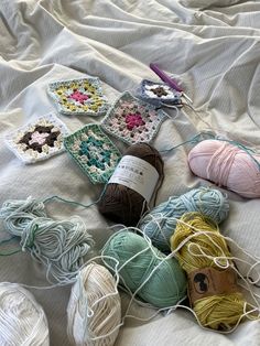 several balls of yarn and crochet on a bed