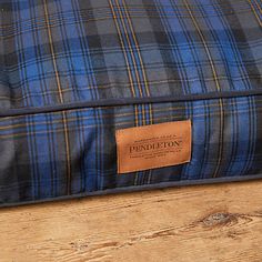 a blue and black plaid pillow sitting on top of a wooden floor