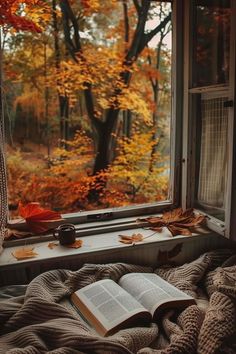 an open book sitting on top of a window sill in front of a forest