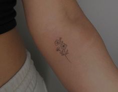 a woman's arm with a small flower tattoo on the left side of her arm