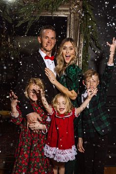 a group of people standing next to each other in front of a mirror with snow falling on them