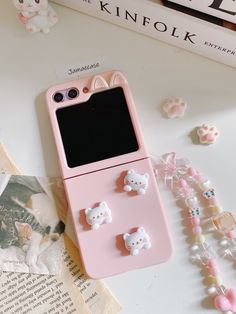 a pink cell phone case with hello kitty decorations on the front and side, sitting next to other accessories