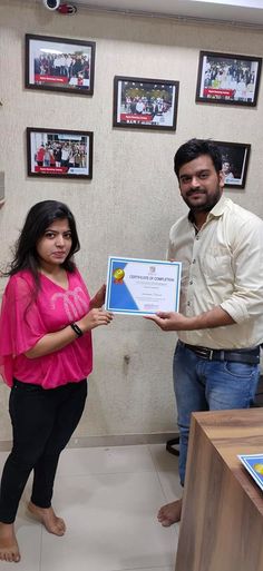 a man holding up a certificate next to a woman