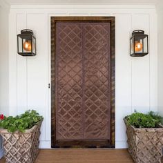 two planters with plants in them are next to a door that has lights on it