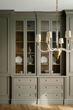 an elegant dining room with gray cabinets and white china cabinetry, gold chandelier