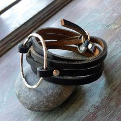 three leather bracelets sitting on top of a rock