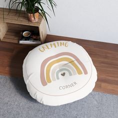 a round floor pillow sitting on top of a wooden table next to a potted plant