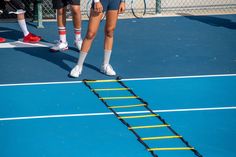 a woman standing on top of a tennis court holding a racquet next to a ladder