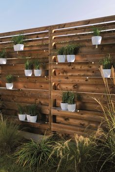 a wooden fence with white planters on it and grass growing in the bottom half