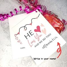 a valentine's day card and candy bag tied to a string on a table