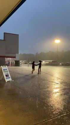 two children playing in an empty parking lot on a rainy day with the sun shining down