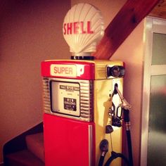 a red and yellow gas pump sitting on top of a wooden table next to a wall