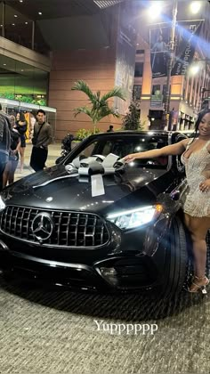 a woman standing next to a black car