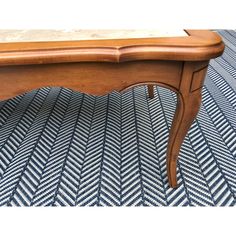 an old wooden table sitting on top of a blue and white patterned carpeted floor