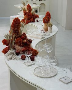 there are many wine glasses and flowers on the counter top in front of each other