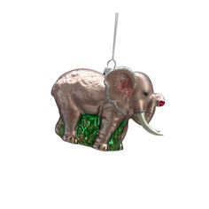 an elephant ornament hanging from a chain on a white background with green grass