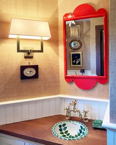 a bathroom sink with a mirror above it and lights on the wall behind it,