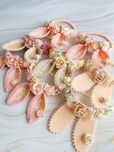 several pairs of pink and white flowered hair clips on a marble surface with pearls