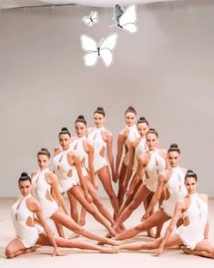 a group of women in white leotards posing for a photo with butterflies above them