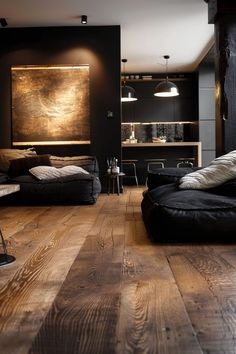 a living room filled with black furniture and wooden flooring next to a painting on the wall