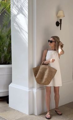 a woman in sunglasses leaning against a pillar