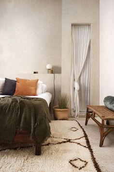 a bedroom with a bed, coffee table and rugs on the floor in front of it